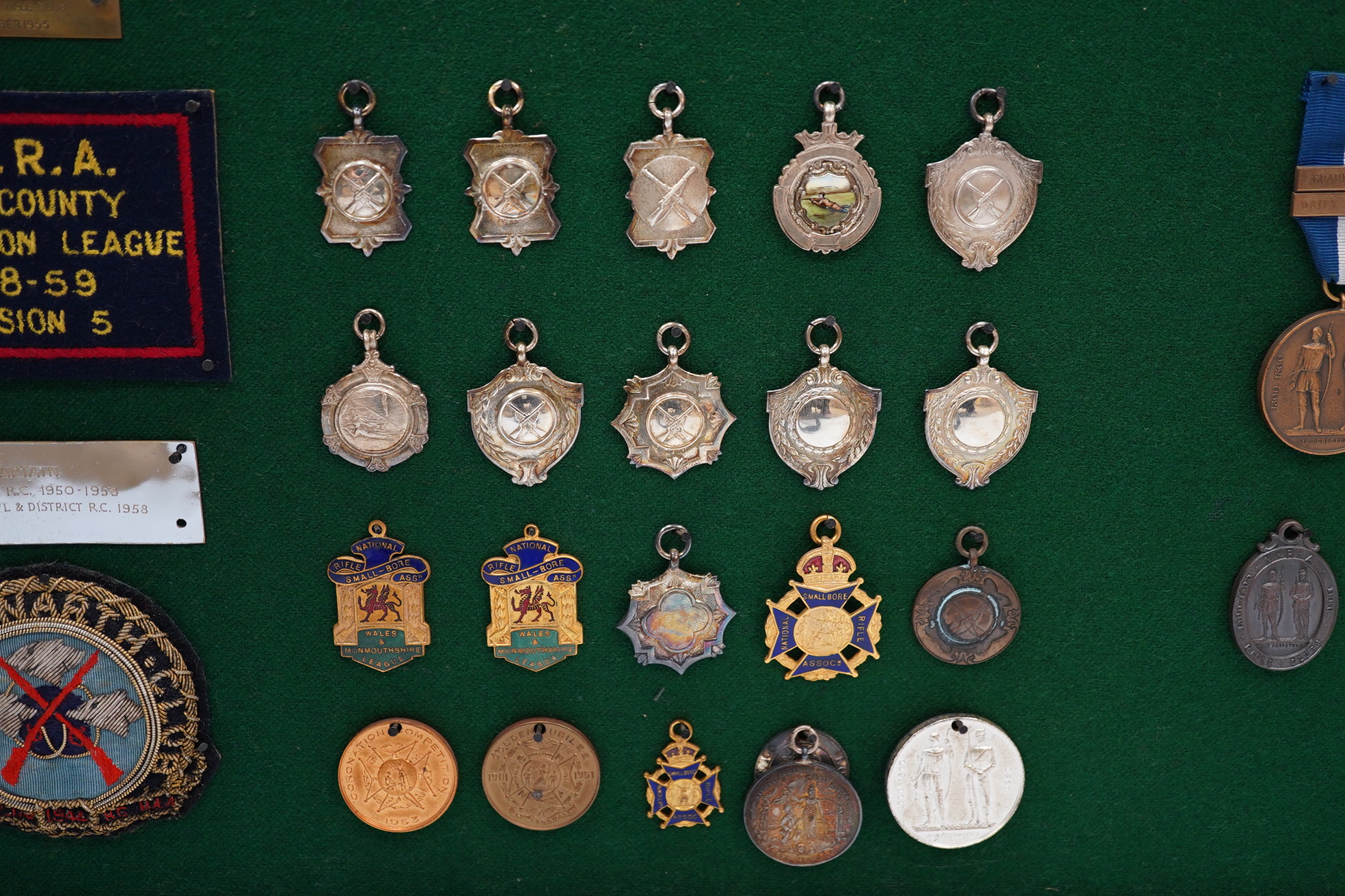 An oak cased collection of rifle and shooting medals disguised as a framed map of Glamorganshire, containing hallmarked silver medals engraved to the awardees, cloth badges for Glamorgan Rifle Association, bronze rifle a